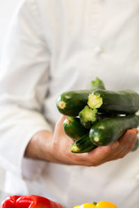 Midsection of male chef holding zucchinis in kitchen