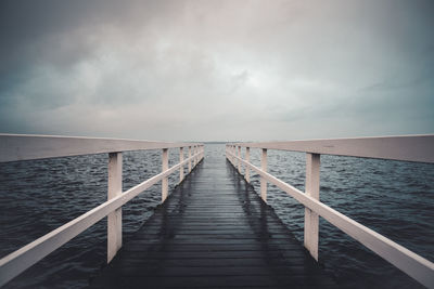 Wooden pier over sea against sky