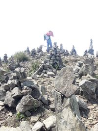 Low angle view of man standing on rock against sky