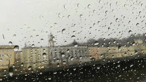 Close-up of wet window against sky