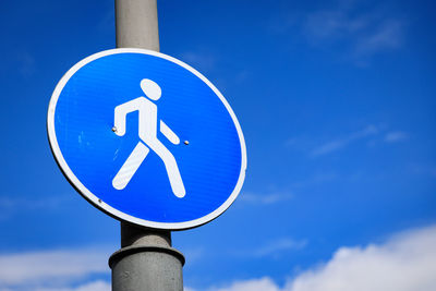 Low angle view of road sign against blue sky