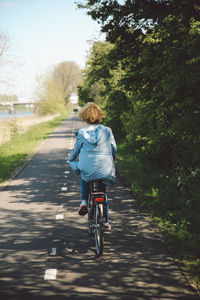 Rear view of woman riding bicycle on road