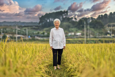 Portrait of smiling old woman standing on field
