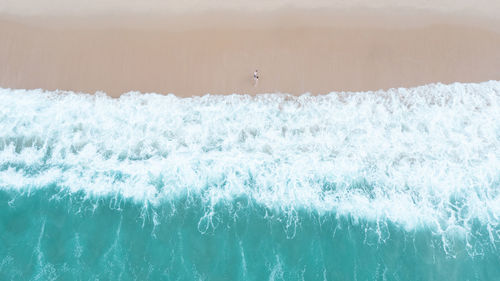 Nature abstract background beautiful sea wave on the sand beach and small tourist couple 