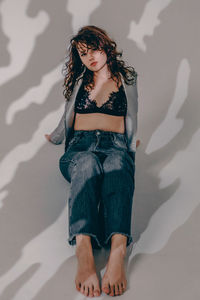 Portrait of young woman standing against wall