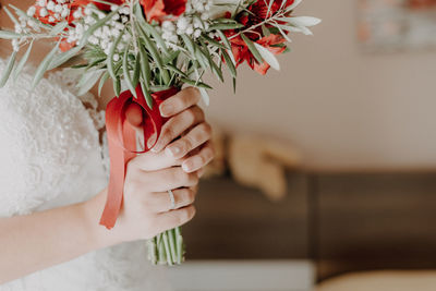 Midsection of bride holding bouquet