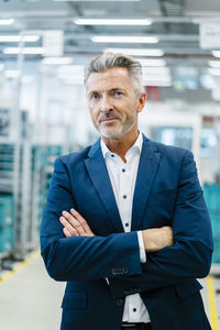 Businessman with arms crossed at automated factory