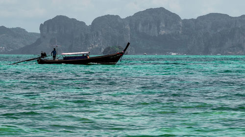 Boat sailing on sea against mountains