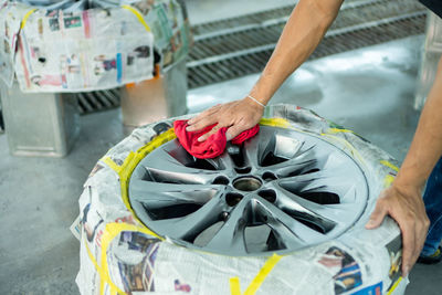 Cropped hand of worker cleaning tire at workshop