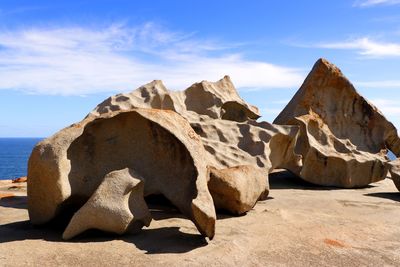 Rock formation by sea against sky