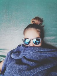 High angle portrait of beautiful woman wearing sunglasses while lying on bed