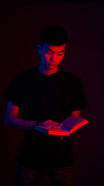 Midsection of man holding illuminated lighting equipment against black background