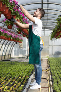 Full length of young man standing by flowering plants
