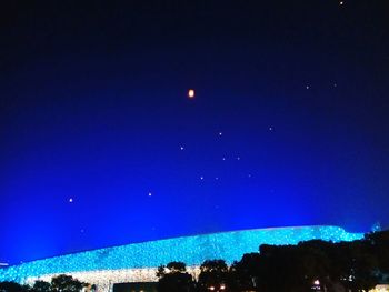 Low angle view of illuminated blue sky at night