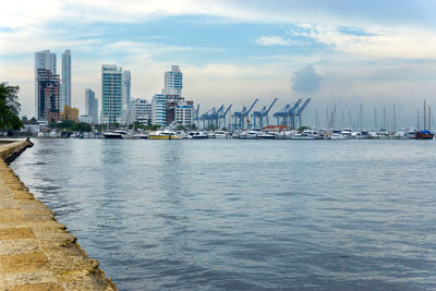 View of harbor in city against sky