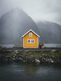 House by lake against sky
