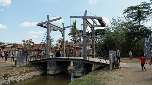 People on bridge over river against sky