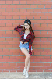 Portrait of a young woman against brick wall