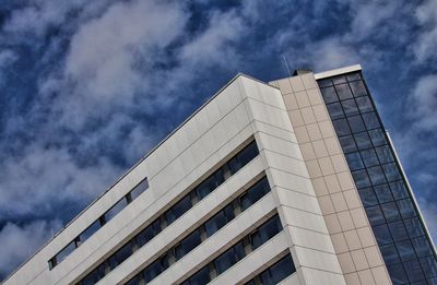 Low angle view of modern building against cloudy sky in city