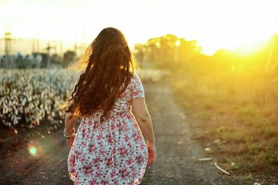 Rear view of a woman walking on landscape against clear sky