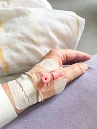 Cropped hand of person with bandages on bed