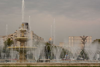 Fountain by building against sky