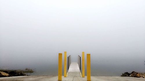 Vanishing pier leading towards lake in foggy weather