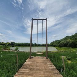 Boardwalk amidst field against sky