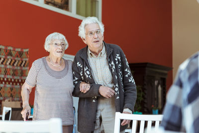 Senior couple standing arm in arm at nursing home