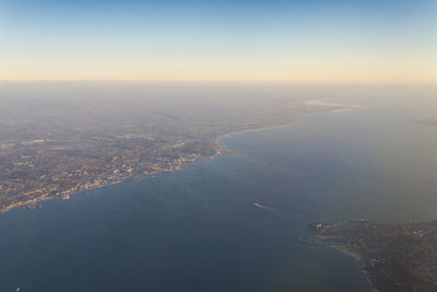 Aerial view of sea and cityscape against sky during sunset