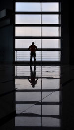 Silhouette man standing against window