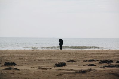 Rear view of silhouette person standing at beach