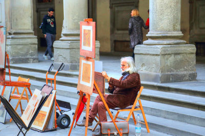 Side view of man sitting on staircase outside building