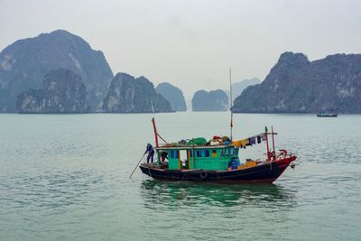 Fishing boat in sea against mountains