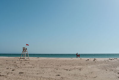 Scenic view couple standing on beach against clear sky