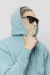 Young man wearing net on face while wearing hoodie