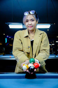 Portrait of young woman playing pool at home