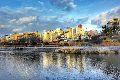 Cityscape by river against sky