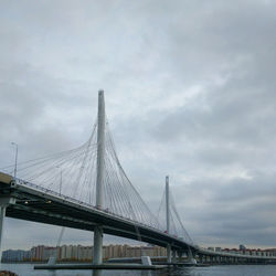 Suspension bridge over river against sky in city