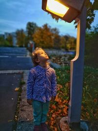 Boy looking at illuminated street light