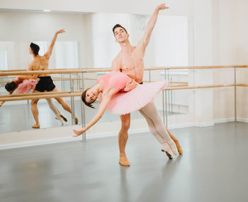 Full length of man and woman practicing ballet dance in studio