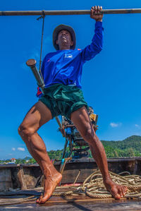 Low angle view of happy man against blue sky