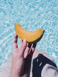 Midsection of person holding ice cream in swimming pool