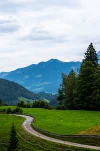 Scenic view of road by mountains against sky