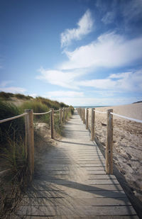 Wooden pier at beach against sky