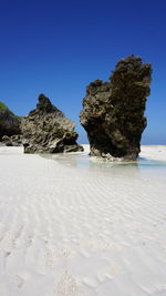 Rock formation on beach against clear blue sky