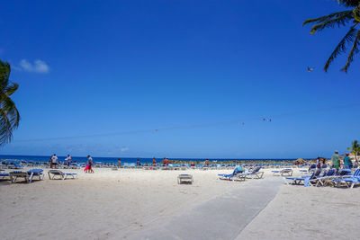 People on beach against clear blue sky