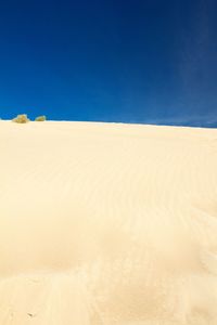 Surface level of sandy beach against clear blue sky