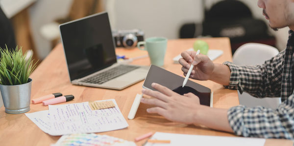 Midsection of man using mobile phone on table