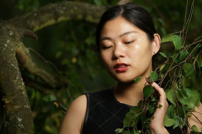 Close-up of young woman amidst tree